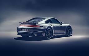 Автомобиль Porsche 911 Turbo S 2020 года на сером фоне вид сзади
