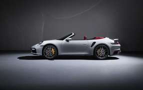 Белый автомобиль Porsche 911 Turbo S Cabriolet 2020 года на сером фоне