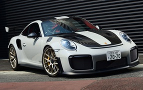 Белый автомобиль Porsche 911 GT2 RS  у черной стены