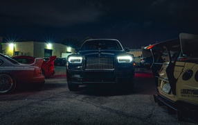 Черный дорогой автомобиль  Rolls-Royce Cullinan, 2020 года с включенными фарами