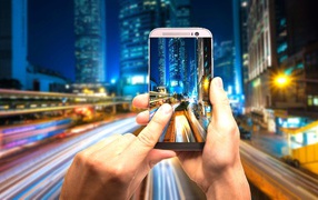 Мужчина делает фото ночного города на смартфон 