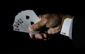 Туз в рукаве у шулера на черном фоне 