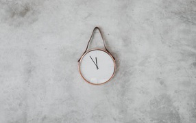Часы с черными стрелками висят на серой стене 