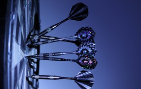 Дротики в доске для дартс на синем фоне 