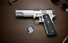 Пистолет Cabot 1911 лежит на столе с очками и жетоном 