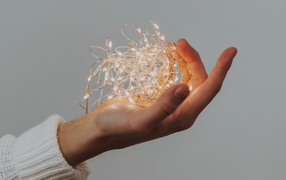 Включенная гирлянда в руке на сером фоне