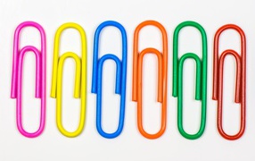 Разноцветные скрепки на белом фоне 