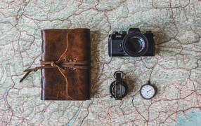 Old camera, compass, clock, notepad and map on the table