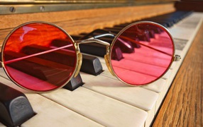 Розовые очки лежат на клавишах рояля