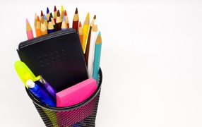 Канцелярские предметы в черном стакане на белом фоне 