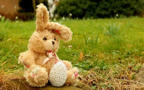 Игрушка заяц на камне в траве