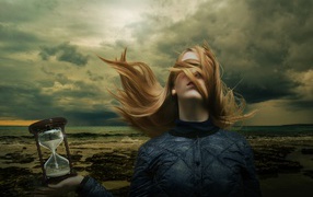 Девушка с волосами на лице держит песочные часы