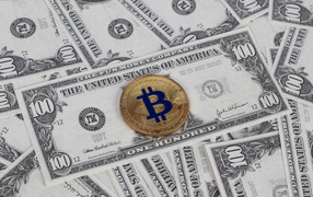 Bitcoin coin lies on hundred dollar bills
