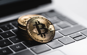 Монеты биткоин лежат на клавиатуре ноутбука 