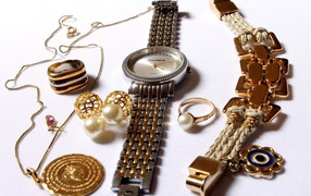 Wrist watch and gold jewelry on white background