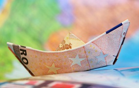 A boat made of euro banknotes on the table