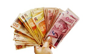 Много купюр бразильского реала в руке на белом фоне 