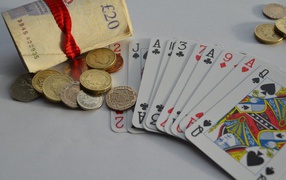 Деньги, монеты и колода карт на столе