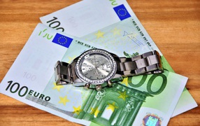 Two hundred euro bills with a clock on the table