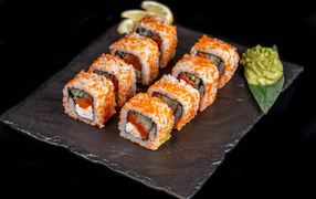 Appetizing Japanese rolls with wasabi sauce on a black background