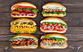 Appetizing hot dogs with different fillings on a wooden table