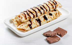 Appetizing thin pancakes on a white plate with chocolate