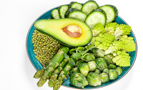 Avocado, cabbage, cucumbers and asparagus on a plate on a white background