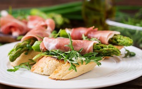 Рулетики с беконом и спаржей на тарелке с гренками