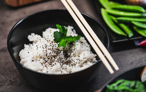 Вареный рис с семенами  в черной миске с палочками