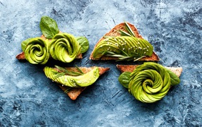 Хлеб с авокадо и базиликом на столе 