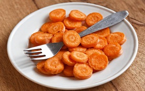 Морковь кружочками на белой тарелке с вилкой