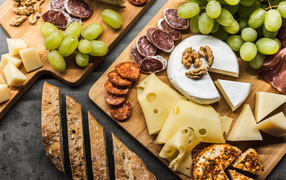 Сыр, колбаса, виноград и батон  на столе 