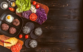 Повар готовит гамбургеры на деревянном столе