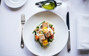 Салат из куриного филе с овощами на белой тарелке