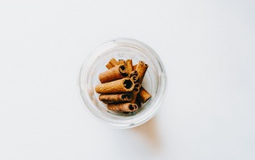 Cinnamon in a glass jar on a white background