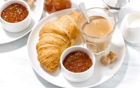 Cocoa on a plate with jam and croissant