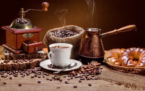 Чашка кофе на столе с круассанами и кофемолкой