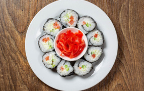 Вкусные суши на большой белой тарелке с имбирем