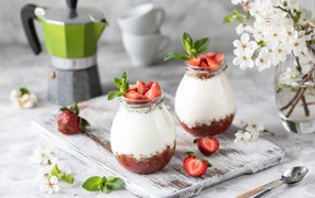 Десерт с йогуртом в банке с клубникой на столе цветами вишни 