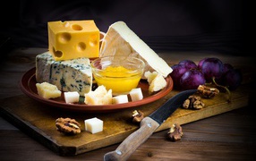 Different types of cheese on the table with grapes and nuts