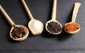 Четыре деревянных ложки со специями на сером столе