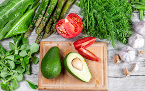 Свежая зелень на столе с авокадо, помидором и чесноком