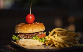 Hamburger with tomato on a board with french fries