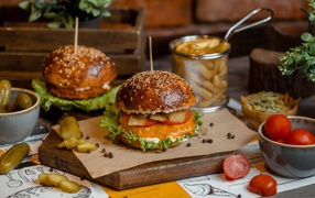 Гамбургеры на столе с помидорами, картофелем фри и солеными огурцами