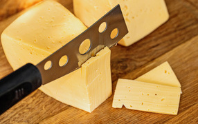 Твердый сыр с ножом на столе