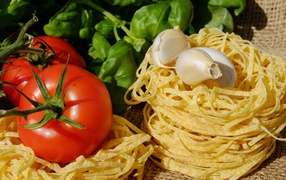 Homemade noodles on the table with tomatoes and basil
