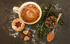 Hot chocolate on the table with a spruce branch, cookies and sweets
