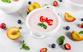 Молочный суп в тарелке на столе с ягодами и нектарином