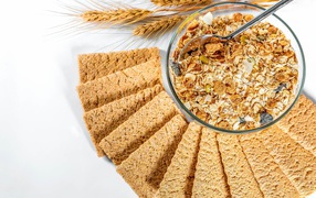 Мюсли в тарелке на столе с хлебцами 