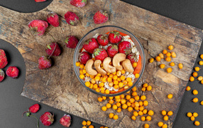 Мюсли с клубникой, орехами и облепихой на доске 